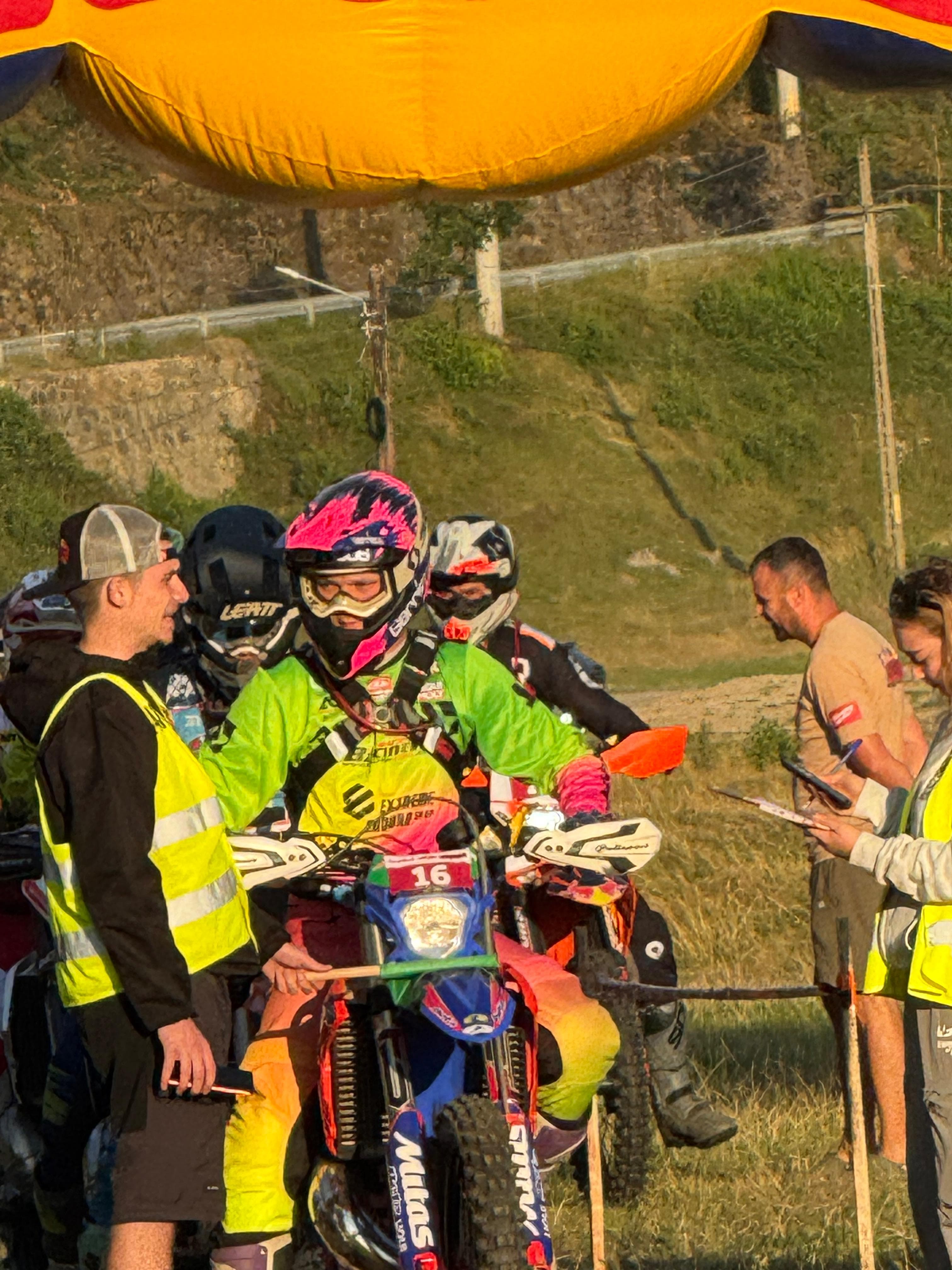 Ein Motocross-Fahrer auf seinem Motorrad spricht mit einem offiziellen Helfer in einer gelben Warnweste.